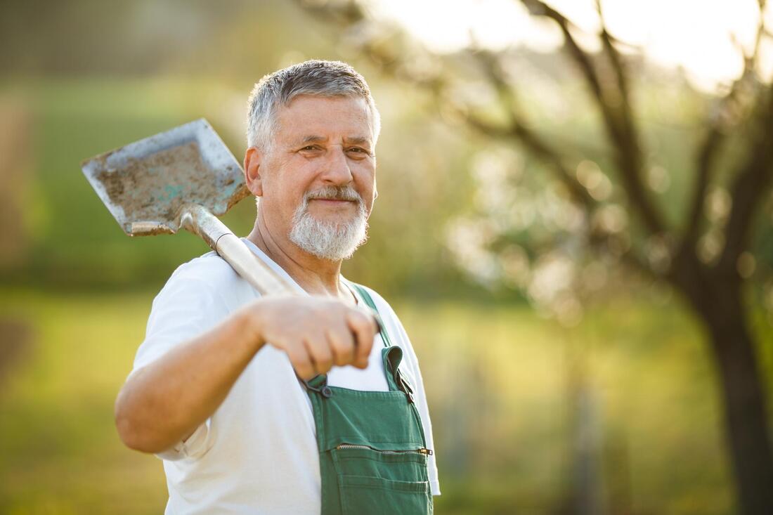 an old man carrying a shovel